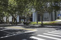 the sidewalk outside of an office building with people walking and sitting on benches in the grass