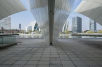 the floor is surrounded by curved architecture with city buildings in the background and a pool of water