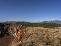 a mountain range that is covered in grass and brown rocks and tall mountains behind it