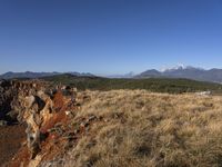 a mountain range that is covered in grass and brown rocks and tall mountains behind it