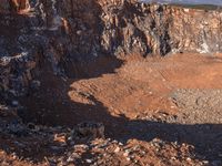 a big open pit is in the middle of mountains with snow covered mountains in the background