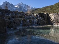 clear water flowing into the pool of an artificial pond surrounded by waterfalls and mountain ranges