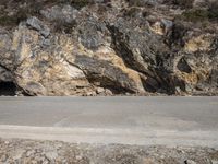 two people riding bikes in front of the cave on the road on a sunny day