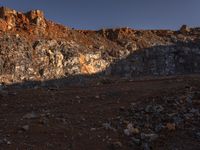 a hill with orange rocks and dirt, with a lone person walking along the sides of it