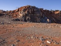 large rock formations near a dirt road and field covered with rocks and trees at the edge of rocky mountain