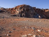 large rock formations near a dirt road and field covered with rocks and trees at the edge of rocky mountain