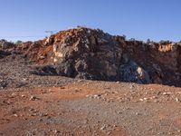 large rock formations near a dirt road and field covered with rocks and trees at the edge of rocky mountain