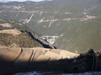 a bridge spanning a wide valley in the mountains in winter, and one of it is not a road