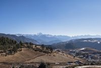 a dirt hill with a snow capped mountain in the back ground and small village on one side