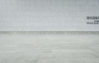 a woman walking in an empty, white brick floored area next to a white building