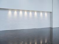 a long room with a white wall that has six lights in the background on each of the walls