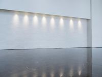 a long room with a white wall that has six lights in the background on each of the walls