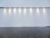 a long room with a white wall that has six lights in the background on each of the walls