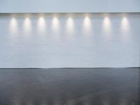 a long room with a white wall that has six lights in the background on each of the walls