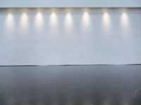 a long room with a white wall that has six lights in the background on each of the walls