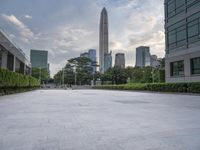 an empty courtyard that is very empty with trees and buildings in the background on a cloudy day