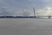 a long bridge in a cloudy sky with mountains behind it and clouds in the background