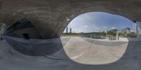 this photo shows a very large mirror at the skate park, with a sky view to the ground and buildings