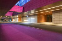 the modern facade of a building at night shows a bright pinkish and light blue sky