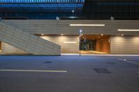 a building at night with light streaming through the windows, lights and stairs to a parking garage