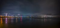 a city is lit up against the water on a cold evening at night and on shore