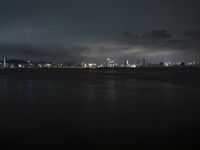 the city and its lighting are dim from a cloudy night sky over the ocean and cityscape