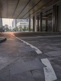 the sidewalk outside of a building and a person on a bicycle in the middle of the street