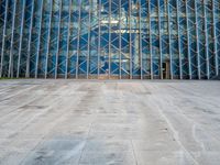 an empty city sidewalk in front of a large glass building with a lot of windows