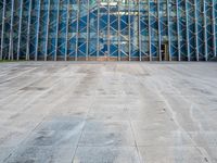 an empty city sidewalk in front of a large glass building with a lot of windows