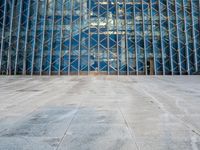 an empty city sidewalk in front of a large glass building with a lot of windows