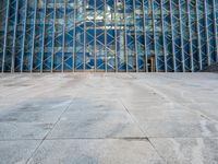 an empty city sidewalk in front of a large glass building with a lot of windows