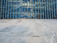 an empty city sidewalk in front of a large glass building with a lot of windows