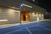 the entrance to an empty building in an urban area at night with a clock on it