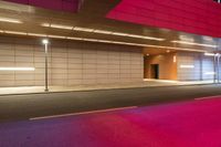 an empty street is lined up with white tiles and bright pink lights in the dark