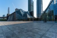 an empty stone floor in front of several modern buildings on a sunny day with bright blue skies