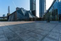 an empty stone floor in front of several modern buildings on a sunny day with bright blue skies