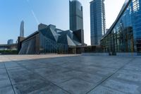 an empty stone floor in front of several modern buildings on a sunny day with bright blue skies