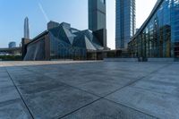 an empty stone floor in front of several modern buildings on a sunny day with bright blue skies