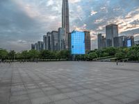 an empty courtyard in front of tall buildings with many people in it and the sky is blue