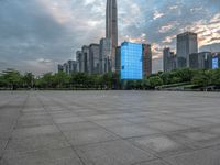 an empty courtyard in front of tall buildings with many people in it and the sky is blue