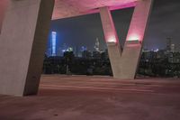 view of a city at night with a pink light on a roof and a pink traffic sign