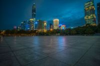 a cityscape lit up at night as the sun sets on the horizon in the background