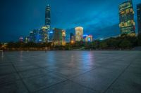 a cityscape lit up at night as the sun sets on the horizon in the background