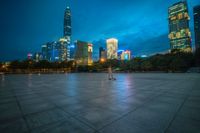 a cityscape lit up at night as the sun sets on the horizon in the background