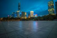 a cityscape lit up at night as the sun sets on the horizon in the background