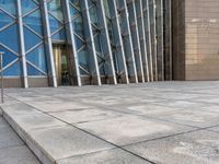 a man wearing glasses with one skateboard on a ledge in front of the entrance of a building