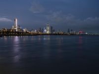 a skyline view of a city at night reflected in the water of lake michigan, with light - up buildings