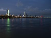 a skyline view of a city at night reflected in the water of lake michigan, with light - up buildings