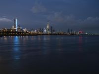 a skyline view of a city at night reflected in the water of lake michigan, with light - up buildings