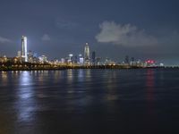 a skyline view of a city at night reflected in the water of lake michigan, with light - up buildings